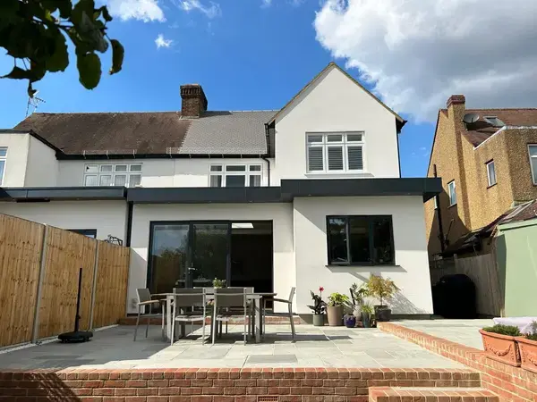 Image of a white house garden extension, walls rendered and painted white to match house. Newly laid patio with new brickwork.