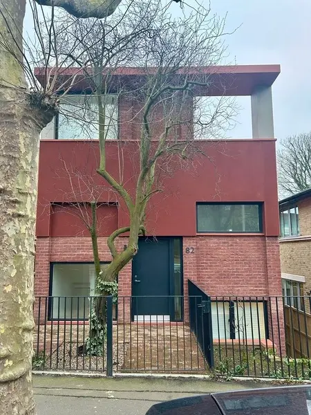 image taken of the front. of a new three story modern house build, bricks are in red.