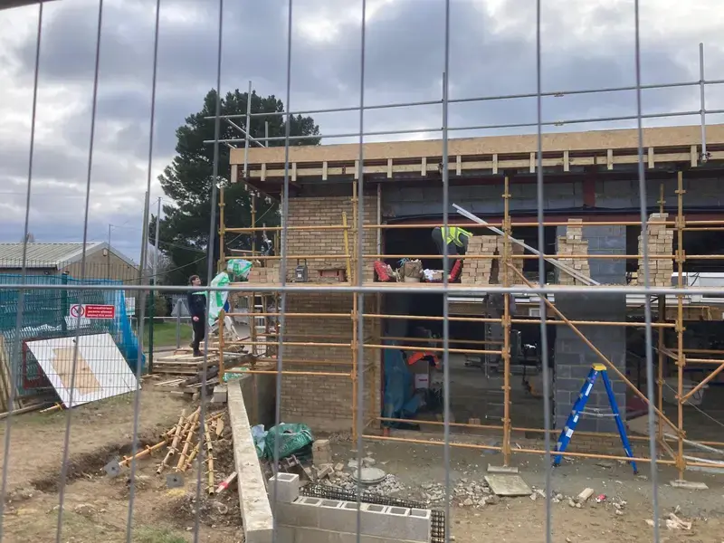 image of a new school extension being built height around six meters, team are laying bricks on second floor level of scaffolding