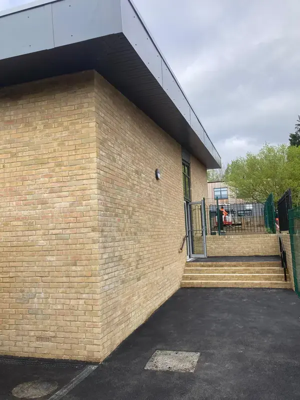 Image of the outside walls of a New School Extension build and four steps with newly laid bricks
