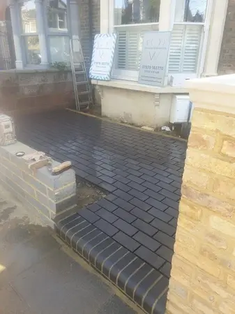 image of a front house garden which has been laid with new black bricks, with some pointing done and remaining pointing to be completed
