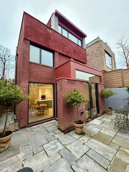 image taken from back, of a new three story modern house build, bricks are in red.